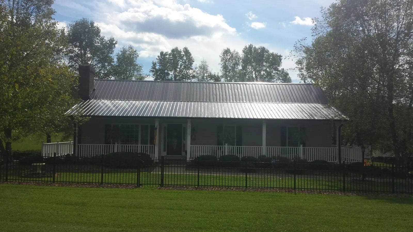 Gray metal roof on a brick ranch with a full width front porch — Gutter Guard Installation work by our crew in Murfreesboro